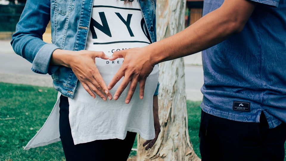 Pregnant belly with heart hands