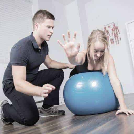 Exercise physiology session with a young woman exerising on a gym ball